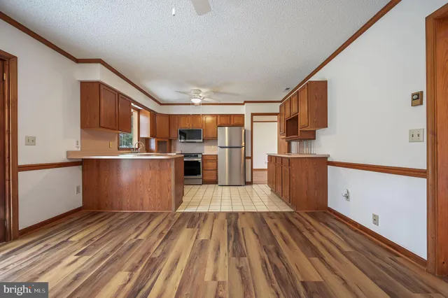 a kitchen with stainless steel appliances granite countertop a refrigerator a stove and a wooden floors