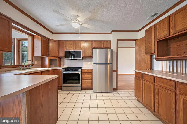 a kitchen with stainless steel appliances granite countertop a refrigerator a stove and a sink with wooden floors