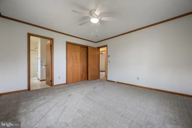 an empty room with closet and a ceiling fan