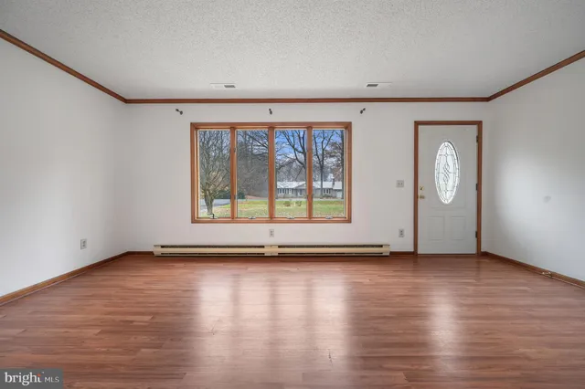an empty room with wooden floor and windows