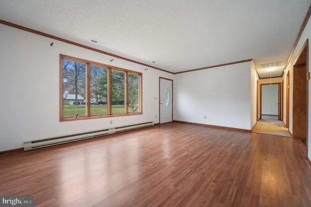 a view of an empty room with wooden floor and a window