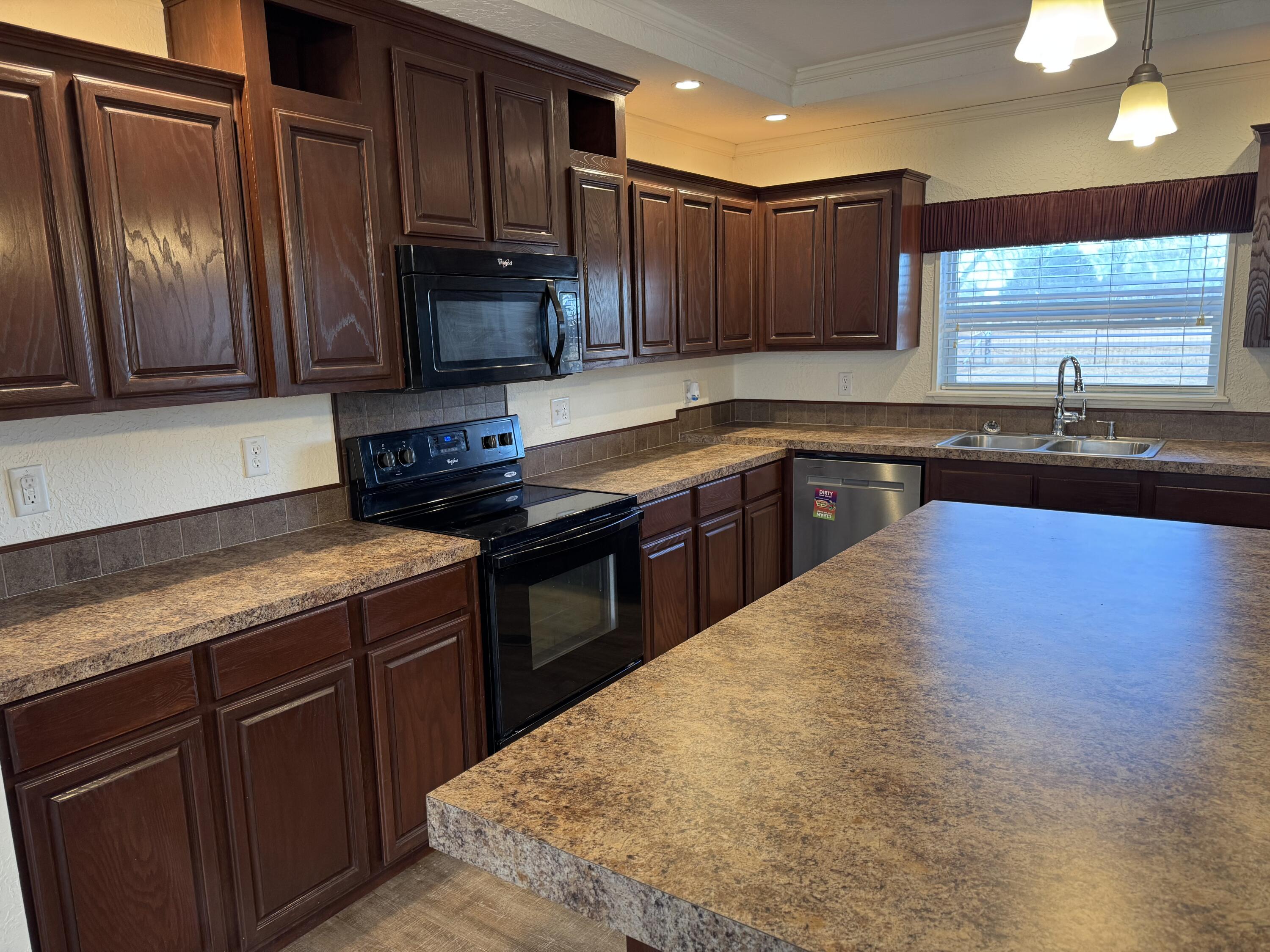 6114 County Road 6500 Lubbock, TX 79403 - Photo 2 of 2 a kitchen with kitchen island granite countertop wooden cabinets stainless steel appliances a sink and a window