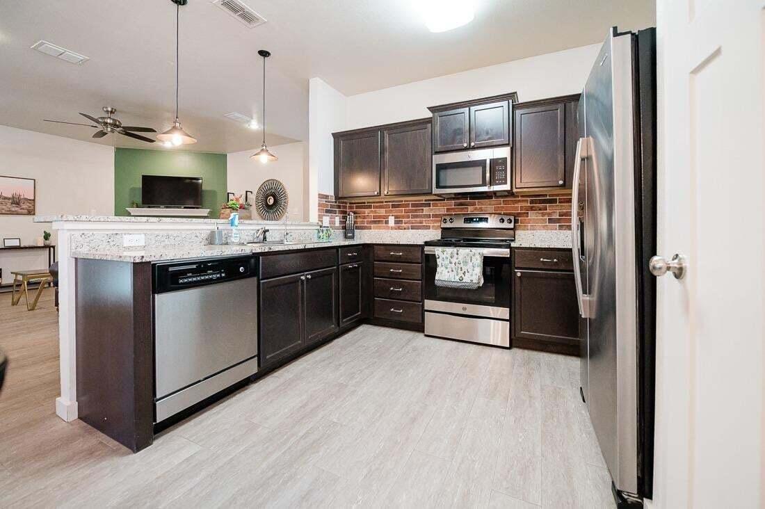 2118 9th Street Lubbock, TX 79401 - Photo 14 of 28 a kitchen with stainless steel appliances granite countertop a stove a sink and a refrigerator