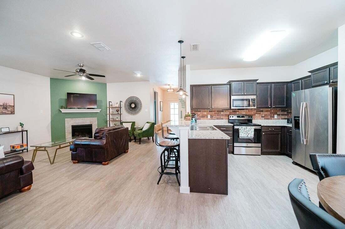 2118 9th Street Lubbock, TX 79401 - Photo 9 of 28 a kitchen with a refrigerator a stove top oven a sink dishwasher and couches with wooden floor