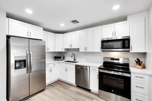 a kitchen with stainless steel appliances a refrigerator a sink a stove a microwave and cabinets