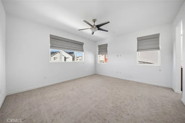 an empty room with windows and ceiling fan