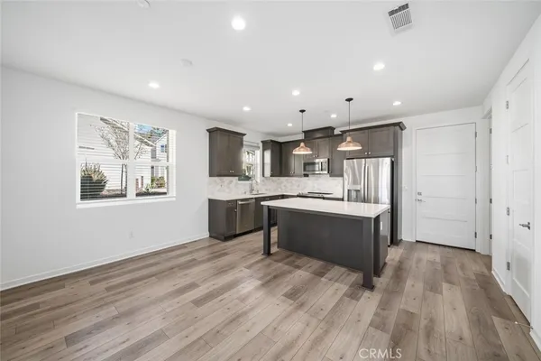 a large kitchen with stainless steel appliances kitchen island a large counter top and a wooden floors