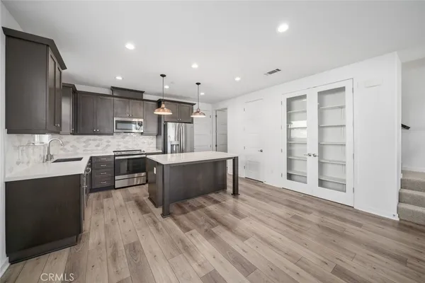 a large kitchen with stainless steel appliances kitchen island granite countertop a large counter top and wooden floors