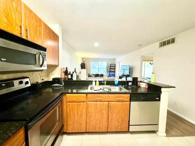 a kitchen with stainless steel appliances granite countertop a stove a sink and a microwave