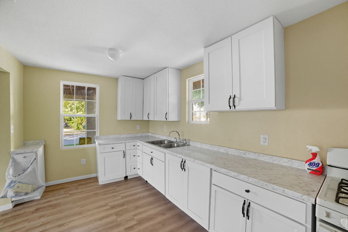 1413 South 2nd Street Temple, TX 76504 - Photo 15 of 24 Kitchen featuring white gas stove, white cabinets, light countertops, and light wood-style flooring