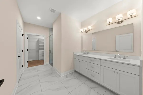a spacious bathroom with a double vanity sink a mirror and a shower