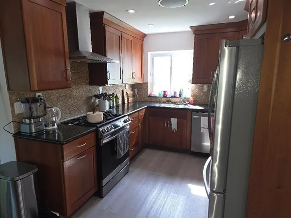a kitchen with stainless steel appliances granite countertop a sink a stove and a refrigerator