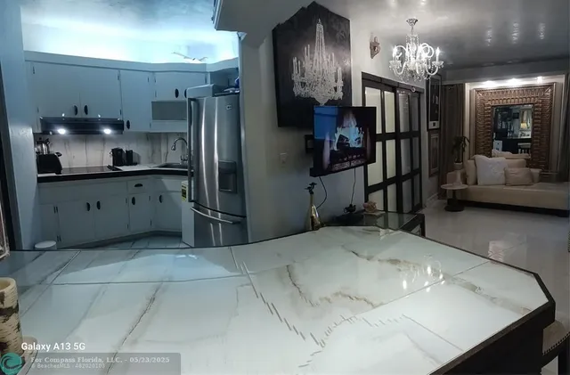 a kitchen with stainless steel appliances kitchen island granite countertop a refrigerator and a sink