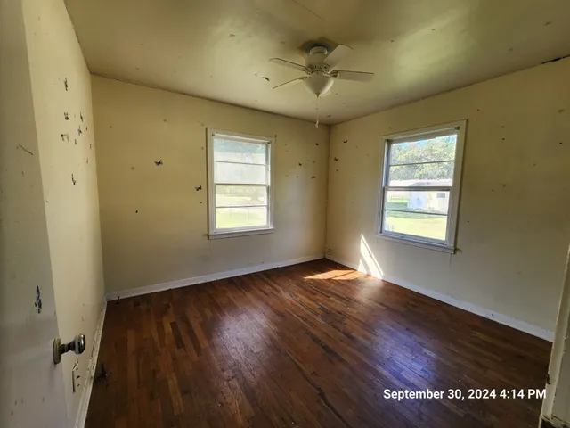 a view of an empty room with a window and wooden floor