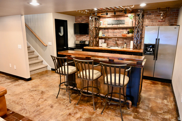 314 Brown Farm Lane Draper, UT 84020 - Photo 23 of 57 Industrial-chic wet bar featuring a wood-finish countertop, exposed brick backsplash, open shelving, and stainless steel appliances