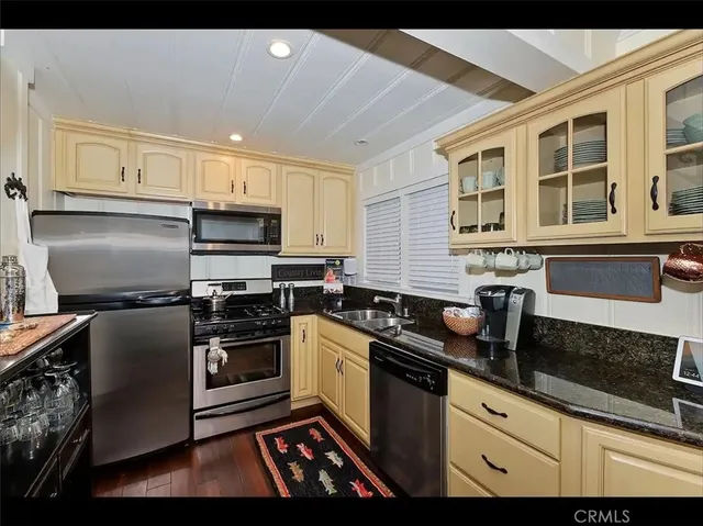 a kitchen with granite countertop a sink stainless steel appliances and cabinets