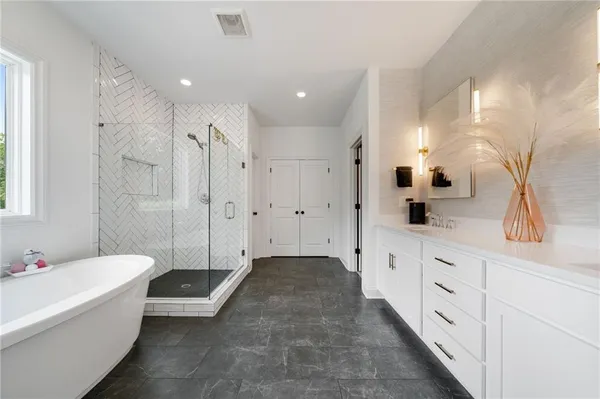 a bathroom with a tub a sink and mirror