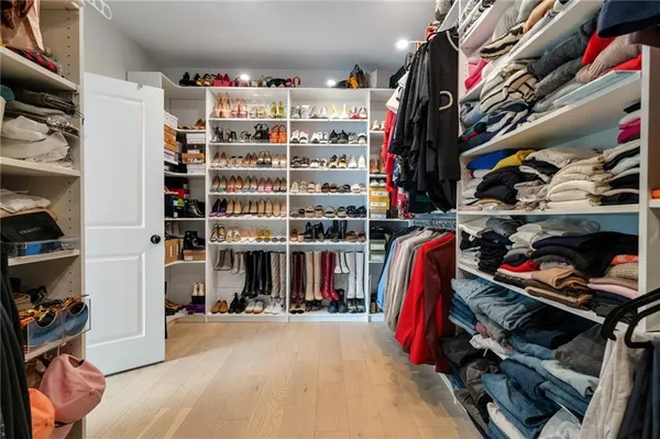 a view of walk in closet with clothes and shoes