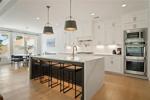 a kitchen with stainless steel appliances granite countertop a stove a sink a microwave a island with a dining table and chairs