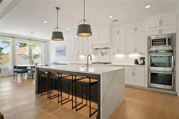a kitchen with stainless steel appliances granite countertop a stove a sink a microwave a island with a dining table and chairs