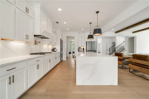 a large white kitchen with lots of counter space wooden floor and appliances