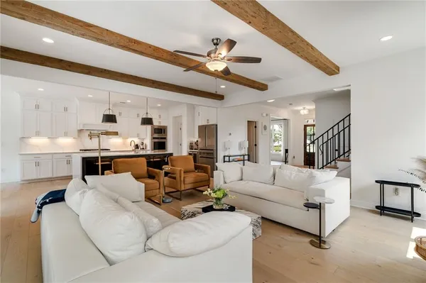 a living room with furniture kitchen view and a chandelier