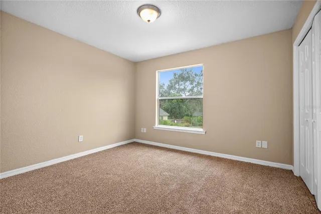 a view of an empty room with window and closet area