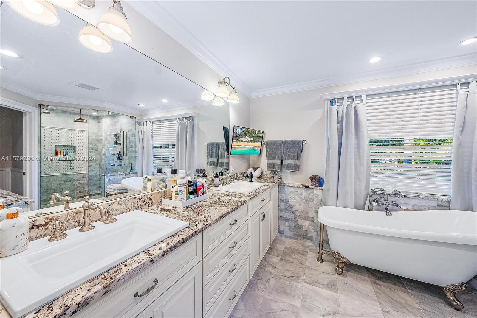 4643 Cheerio Way Stuart, FL 34997 - Photo 42 of 69 a bathroom with double vanity sinks a large mirror and a bathtub next to a window
