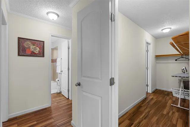 a view of a hallway with wooden floor and closet area