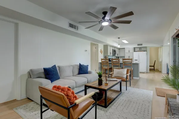 a living room with furniture kitchen view and a chandelier