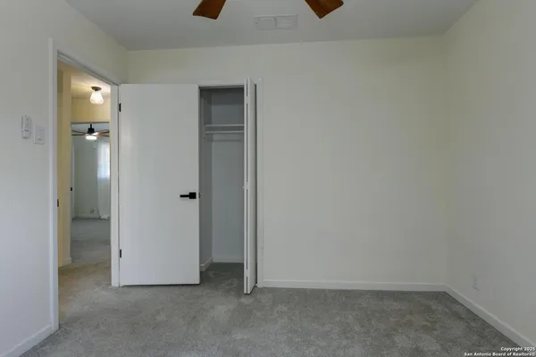an empty room with a window and a fan