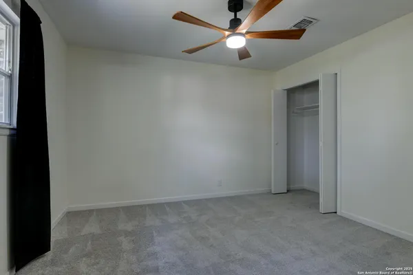 an empty room with a window and a fan