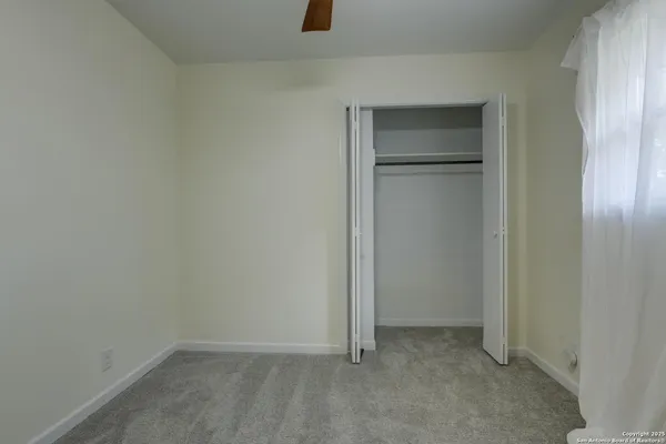 an empty room with a window and a fan