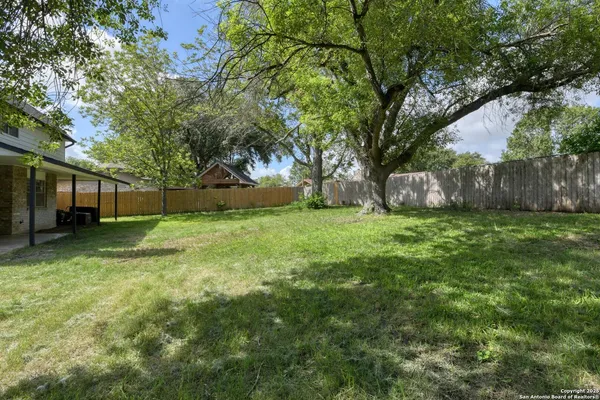 a view of a house with a yard and a large tree