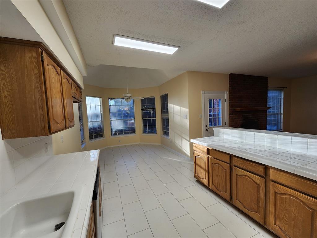2413 Timber Ridge Lane Flower Mound, TX 75028 - Photo 9 of 32 Kitchen area featuring wood cabinetry, white tile countertops, and white tile flooring