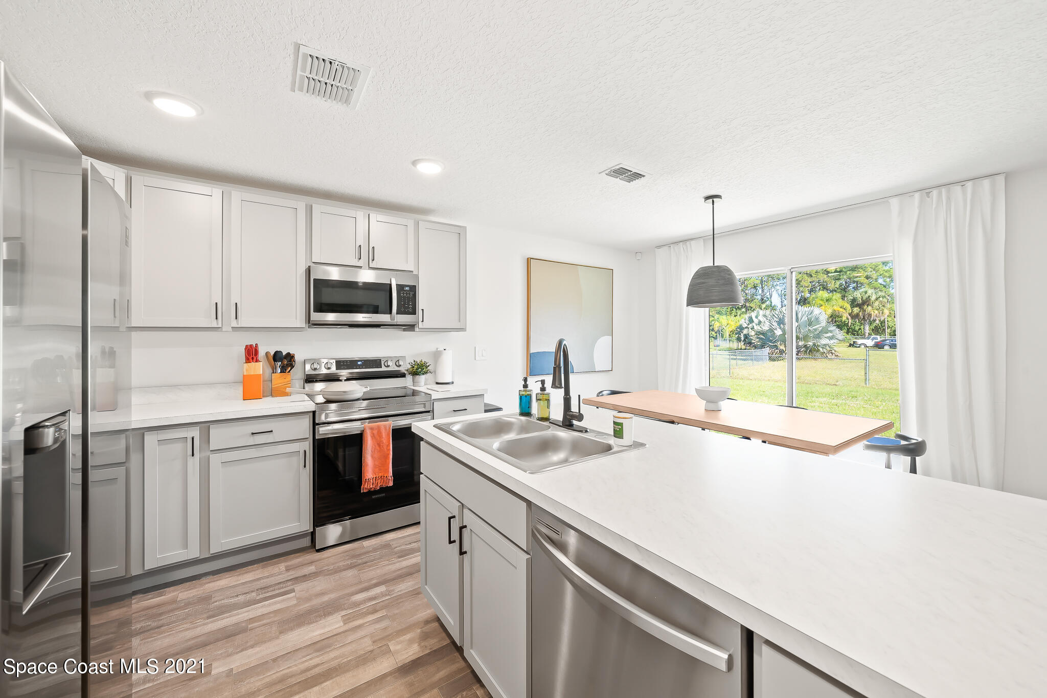 271 Wendover Road Southwest Palm Bay, FL 32908 - Photo 7 of 35 a kitchen with a sink a stove a microwave and wooden cabinets