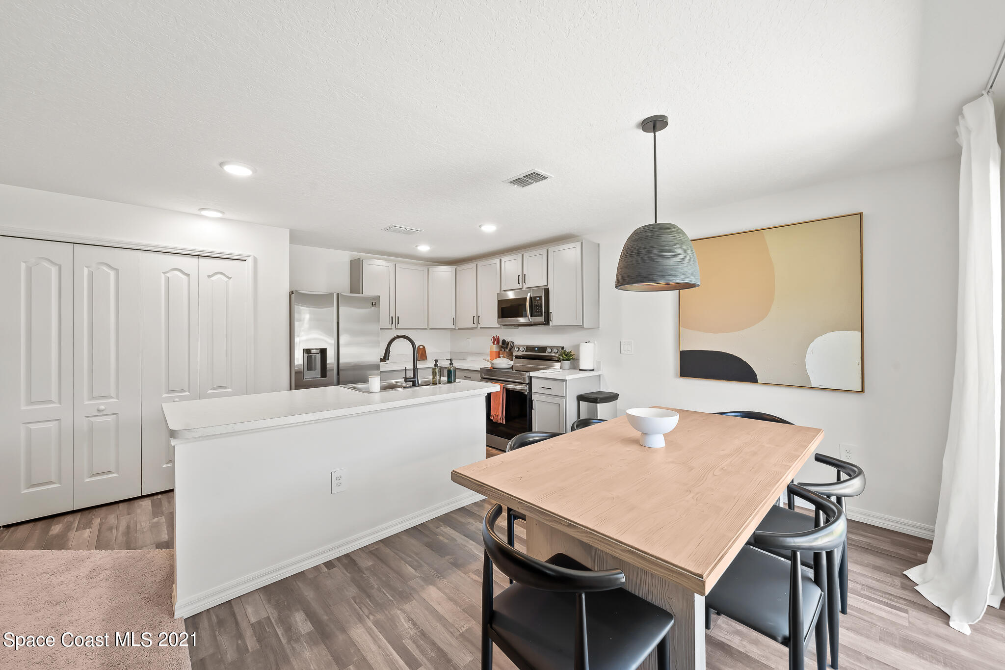 271 Wendover Road Southwest Palm Bay, FL 32908 - Photo 8 of 35 a kitchen with kitchen island a stove a table and chairs in it