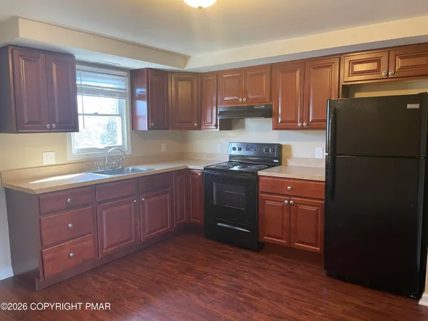 a kitchen with granite countertop wooden cabinets and refrigerator
