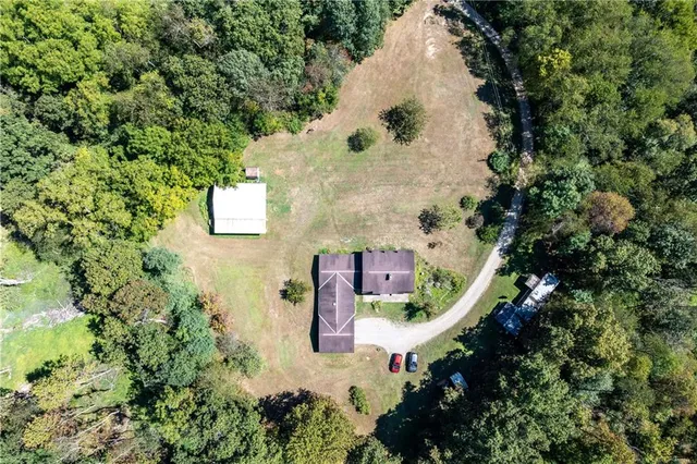 an aerial view of residential house with outdoor space and trees all around