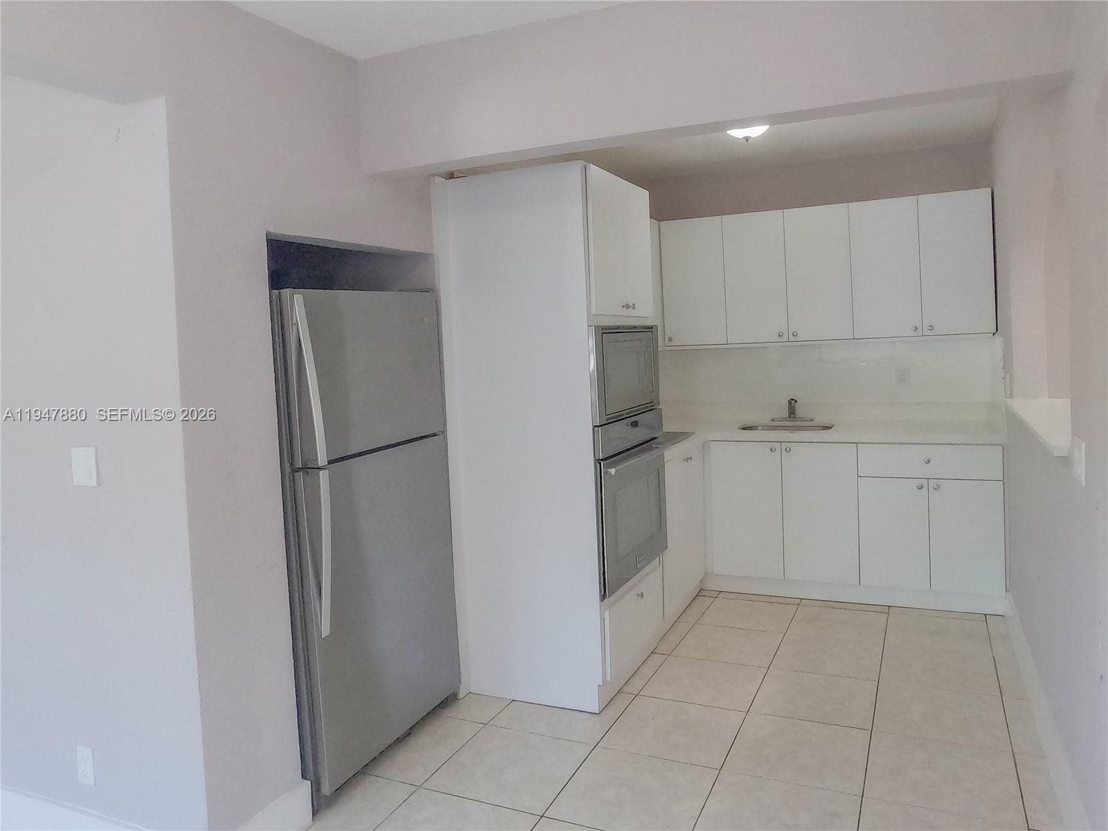 1051 Northwest 63rd Street Miami, FL 33150 - Photo 18 of 30 a kitchen with white cabinets and refrigerator