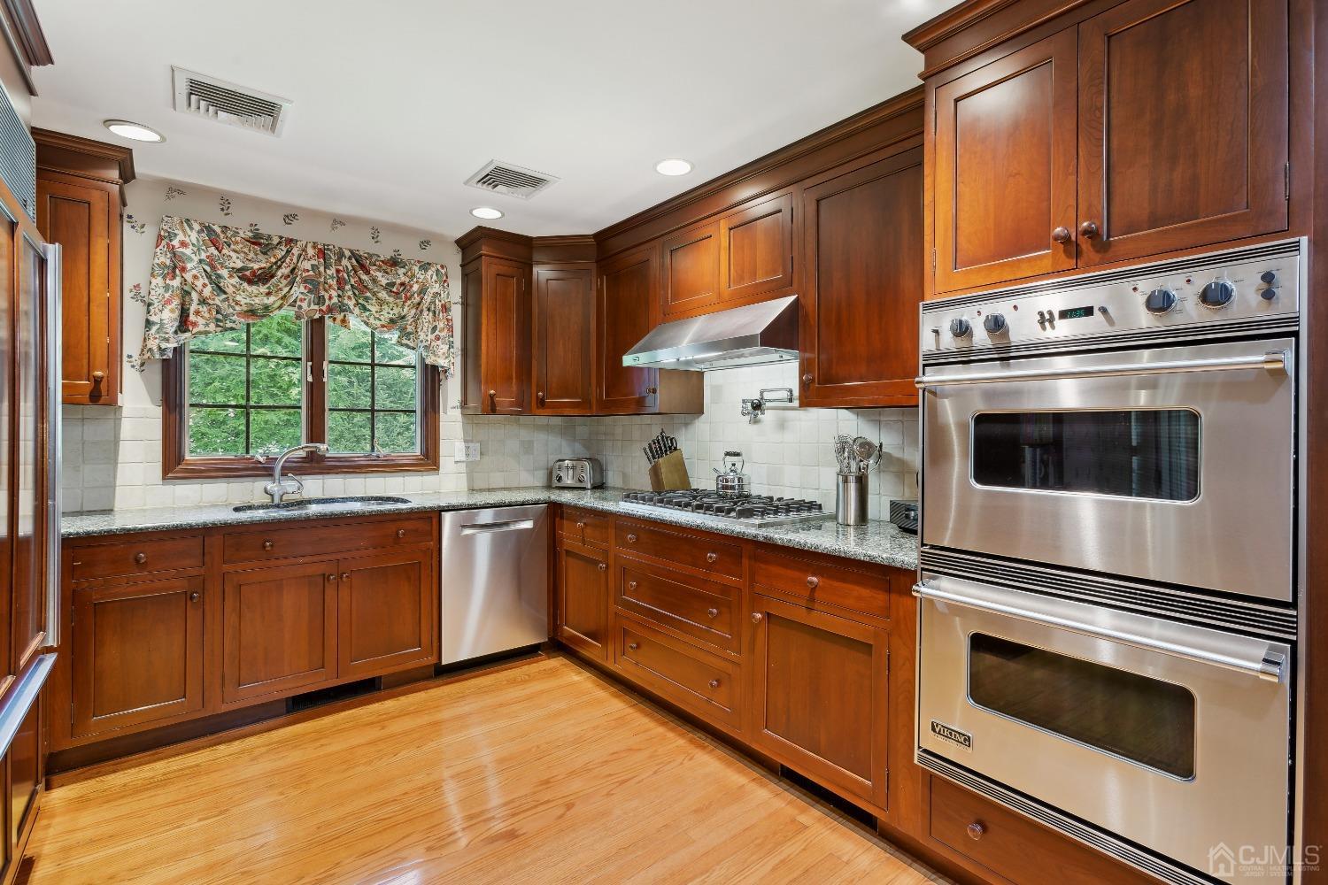 32 Oak Hills Road Edison, NJ 08820 - Photo 21 of 54 a kitchen with granite countertop wooden cabinets stainless steel appliances and a large window