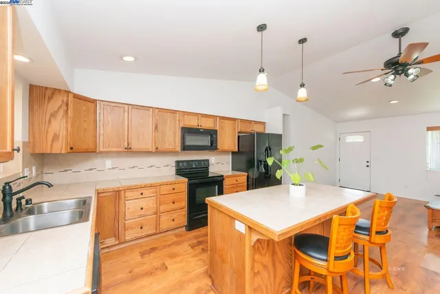 a kitchen with stainless steel appliances kitchen island granite countertop a sink a stove and a refrigerator