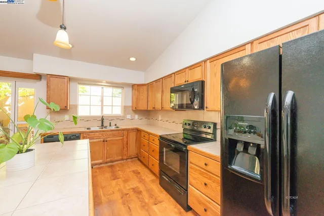 a large kitchen with stainless steel appliances granite countertop a refrigerator and a stove top oven