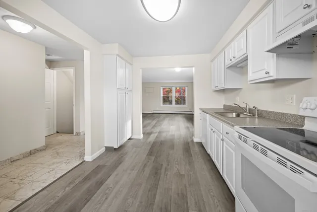 a kitchen with granite countertop wooden floors a sink and stainless steel appliances
