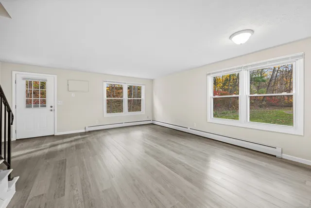 an empty room with wooden floor and windows
