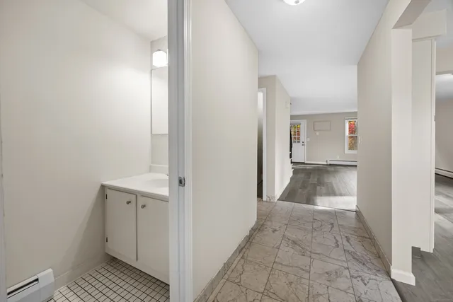 a view of a hallway with wooden floor and a bathroom