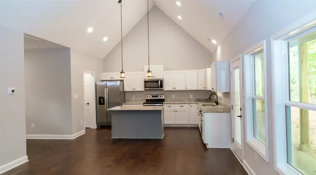 a kitchen with stainless steel appliances a refrigerator a sink dishwasher a stove and white cabinets with wooden floor