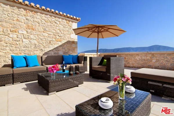 a view of a patio with couches table and chairs under an umbrella