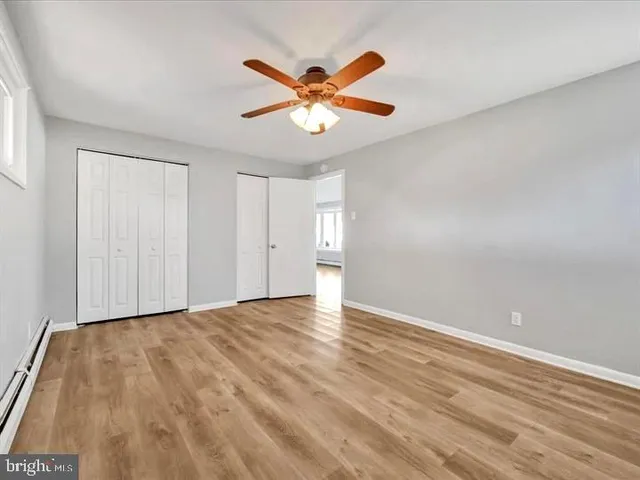 a view of an empty room with window and a ceiling fan