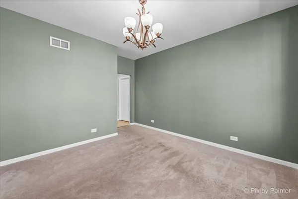 a view of an empty room with a chandelier fan